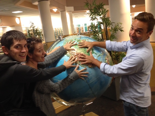 Dan Cockayne, Jessi Breen, and Andy Schooner touch a big globe (featuring crazy vertical exaggeration in the topography) at the Lexington Public Library